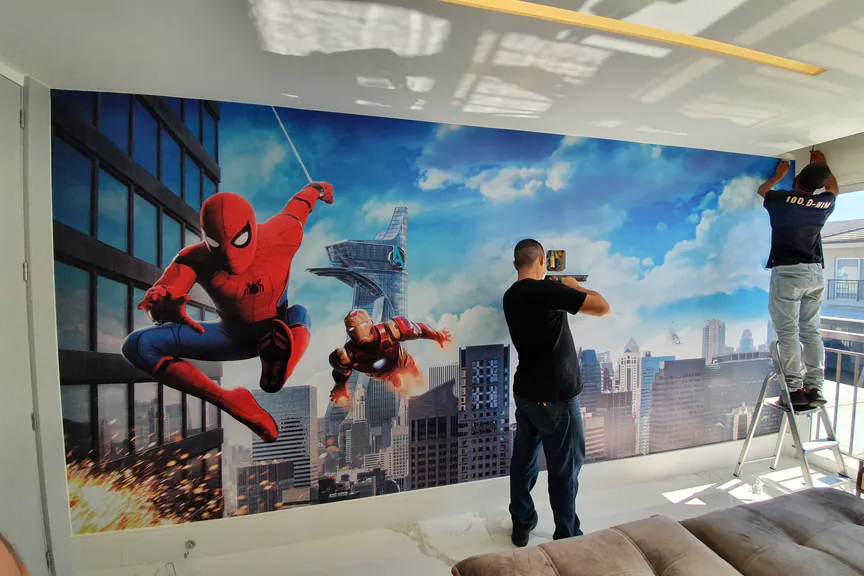 Painel adesivo do Homem-Aranha sendo instalado na parede de um ambiente interno